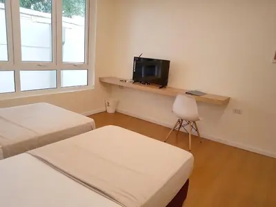 a room with two beds and a tv and a chair at The Leaf House in Manila