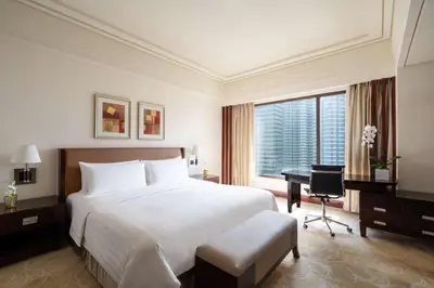 a bedroom with a large white bed and a desk at Edsa Shangri-La, Manila in Manila