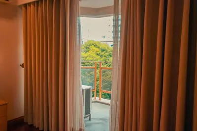 a window with an open curtain with a view of a balcony at City Garden Suites Manila in Manila