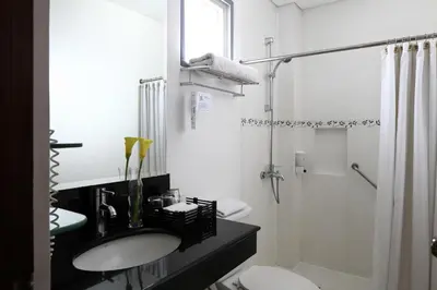 a white bathroom with a sink and a shower at Manila Lotus Hotel in Manila