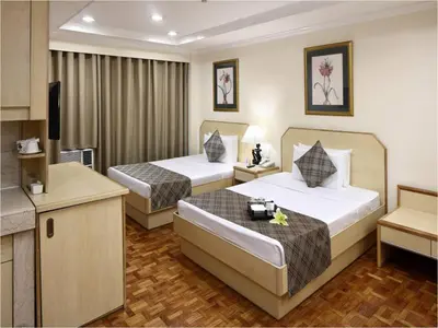 a hotel room with two beds and a television at Manila Lotus Hotel in Manila