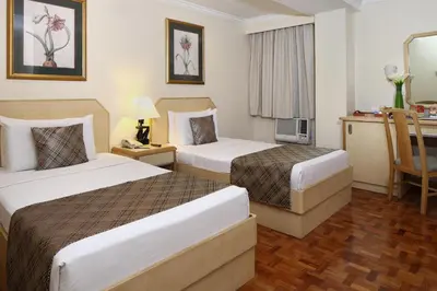a hotel room with two beds and a desk at Manila Lotus Hotel in Manila