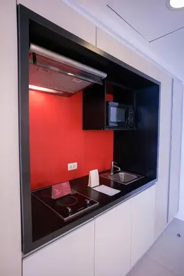 a kitchen with a sink and a red wall at The Picasso Boutique Serviced Residences Managed by HII in Manila