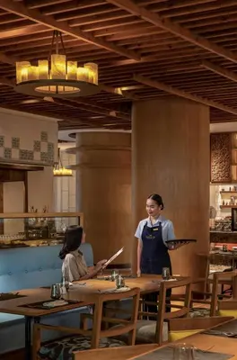two people sitting at tables in a restaurant at Dusit Thani Manila in Manila