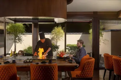 two men cooking food at a table in a restaurant at Dusit Thani Manila in Manila