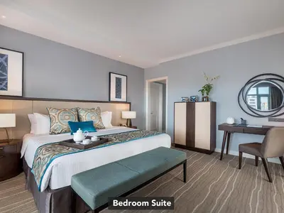 a bedroom with a bed with a table and a chair at Ascott Makati in Manila