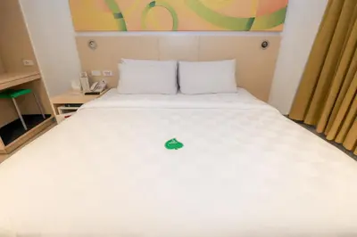 a bed in a hotel room with a green apple on it at Go Hotels Ermita, Manila in Manila