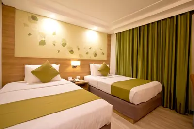 two beds in a hotel room with green curtains at Crown Regency Hotel Makati in Manila
