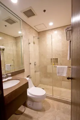 a bathroom with a toilet and a sink and a shower at Crown Regency Hotel Makati in Manila