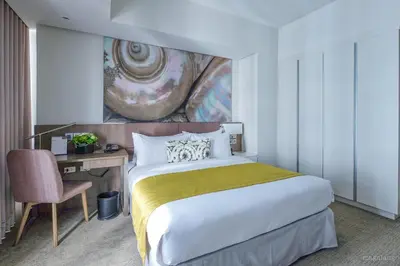 a bedroom with a bed and a desk and a painting at Citadines Millennium Ortigas Manila in Manila