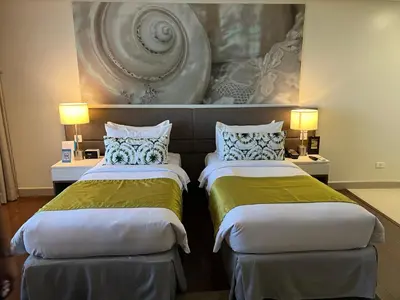 two beds in a hotel room with a painting on the wall at Citadines Millennium Ortigas Manila in Manila