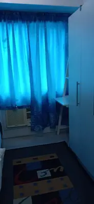 a room with a blue curtain and a window at Chin's Place Sea Residences MOA in Manila