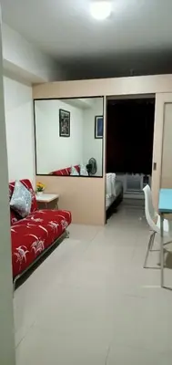 a living room with a red bed and a table at Chin's Place Sea Residences MOA in Manila