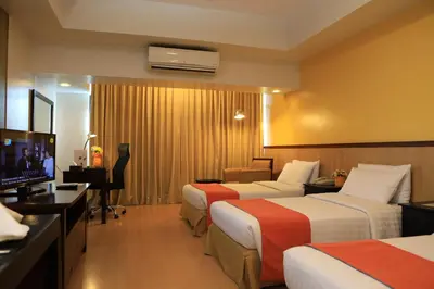 a hotel room with two beds and a flat screen tv at The Malayan Plaza Hotel in Manila