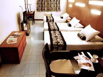 a hotel room with four beds and a table and chairs at Jupiter Suites in Manila