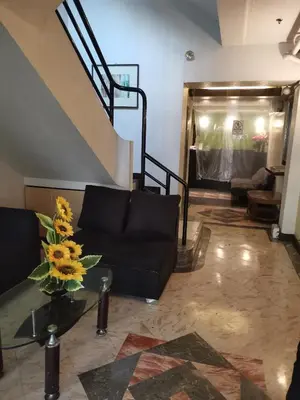 a living room with a black couch and a staircase at Jupiter Suites in Manila