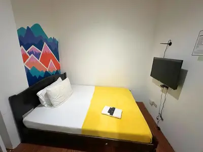 a small bedroom with a bed with a tv on it at Dormitelsph España in Manila
