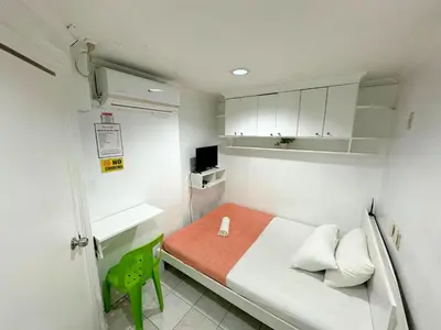 a small room with a bed and a green chair at Dormitelsph España in Manila