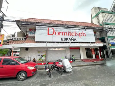 a red car parked in front of a building with two motorcycles at Dormitelsph España in Manila