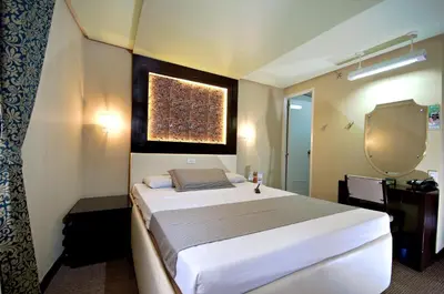 a bedroom with a large white bed and a mirror at Eurotel Makati in Manila