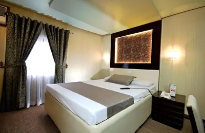 a bedroom with a large bed and a window at Eurotel Makati in Manila