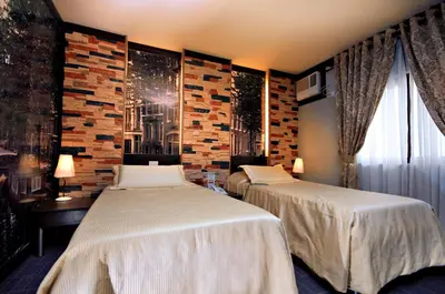 a bedroom with two beds and a brick wall at Eurotel Makati in Manila