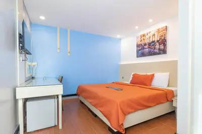 a blue bedroom with a bed with an orange blanket at Eurotel Pedro Gil in Manila