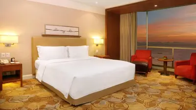 a bedroom with a large white bed and a red chair at New Coast Hotel Manila in Manila