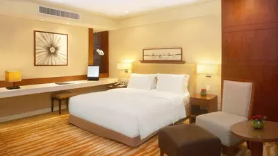 a bedroom with a large white bed and a desk at New Coast Hotel Manila in Manila