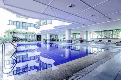 a large pool in a building with tables and chairs at Makati Palace Hotel in Manila