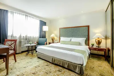 a hotel room with a large bed and a desk at Makati Palace Hotel in Manila