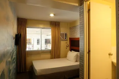 a small bedroom with a bed and a window at Spaces Hotel Makati in Manila