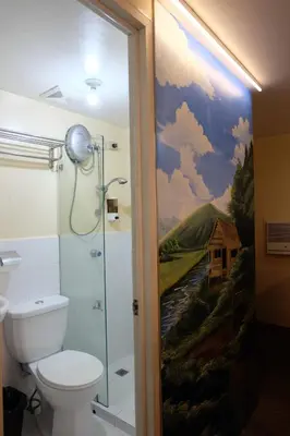 a bathroom with a shower and a painting on the wall at Spaces Hotel Makati in Manila