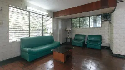 a living room with two green chairs and a couch at RedDoorz at Broadway Court Apartelle Quezon City in Manila