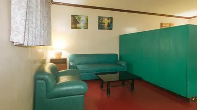 a living room with a green chair and a table at RedDoorz at Broadway Court Apartelle Quezon City in Manila