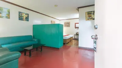 a living room with a couch and a bed at RedDoorz at Broadway Court Apartelle Quezon City in Manila
