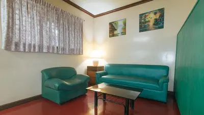 a living room with two green chairs and a table at RedDoorz at Broadway Court Apartelle Quezon City in Manila