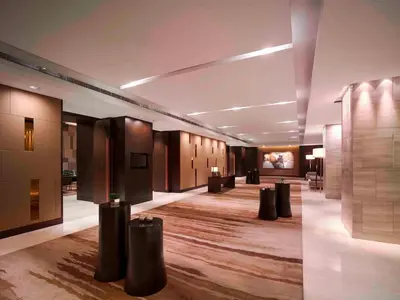 a lobby of a building with tables and chairs at New World Makati Hotel, Manila in Manila