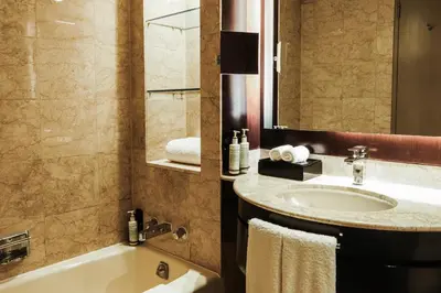 a bathroom with a sink and a tub and a mirror at New World Makati Hotel, Manila in Manila