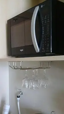 a microwave on a shelf above some wine glasses at Yong's Place at Vista Residences Taft in Manila
