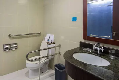 a bathroom with a toilet and a sink and a mirror at Microtel by Wyndham Mall of Asia in Manila