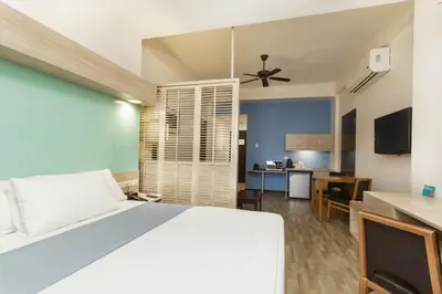 a bedroom with a white bed and a kitchen at Microtel by Wyndham Mall of Asia in Manila