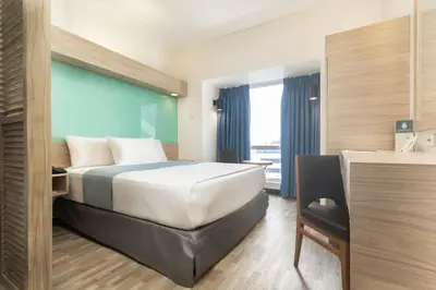 a bedroom with a bed and a desk and a chair at Microtel by Wyndham Mall of Asia in Manila