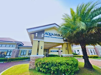 a building with a palm tree in front of it at Aquamira Hotel & Resort in Tanza