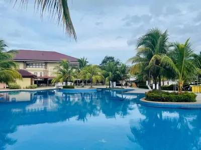 a large pool with palm trees in front of a building at Aquamira Hotel & Resort in Tanza
