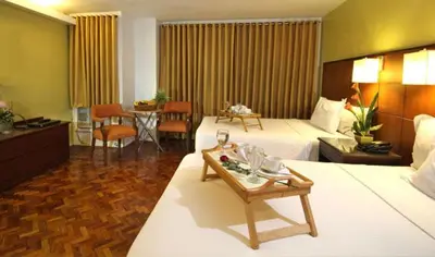 a large hotel room with two beds and a table at Comfy Inn Manila-Kalaw in Manila