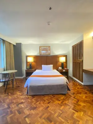 a bedroom with a large bed and a wooden floor at Comfy Inn Manila-Kalaw in Manila