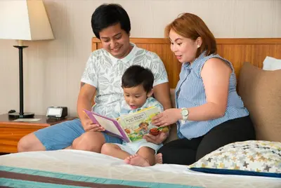 a man and a woman reading a book to a child at Hotel Kimberly Manila in Manila
