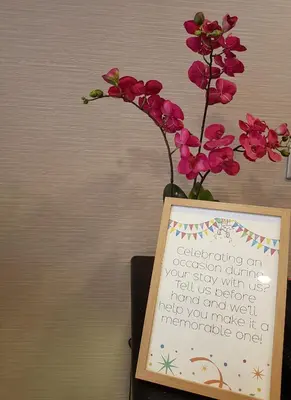 a vase with a flower on a table next to a sign at Hotel Kimberly Manila in Manila