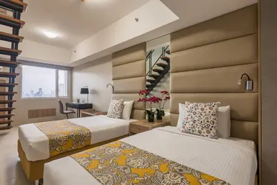 a hotel room with two beds and a staircase at Hotel Kimberly Manila in Manila